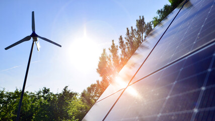 Solar panels with wind turbine on blue sky. Concept of clean energy. Green technology for future. 