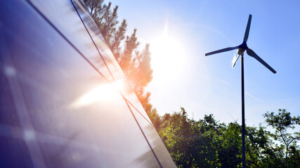 Solar panels with wind turbine on blue sky. Concept of clean energy. Green technology for future. 