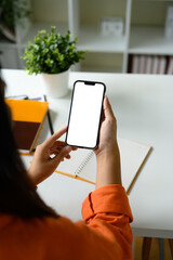 Female hand holding smartphone with a blank screen in a bright office