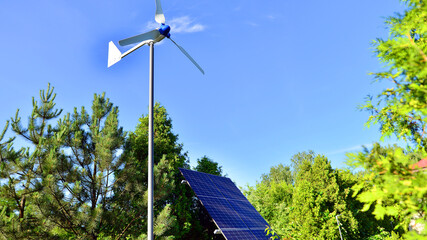 Solar panels with wind turbine on blue sky. Concept of clean energy. Green technology for future. 