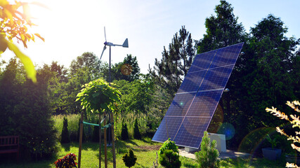 Solar panels with wind turbine on blue sky. Concept of clean energy. Green technology for future. 