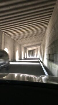 Driving in a tunnel on Spl&uuml;gen Pass. Motorway tunnel in Italian alps: diminishing perspective view of concrete corridor with light coming from arch-shaped windows