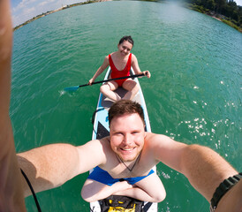Couple Paddleboarding on a Sunny Lake