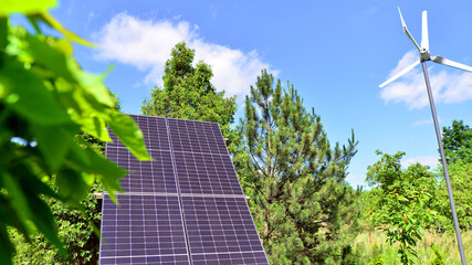 Solar panels with wind turbine on blue sky. Concept of clean energy. Green technology for future. 