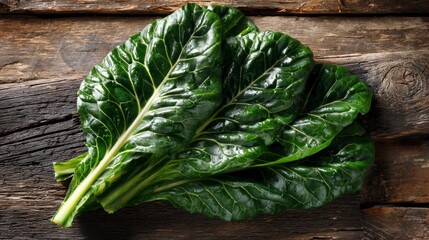Fresh green Swiss chard leaves with prominent veins, arranged on rustic wood with sunlight highlighting their glossy texture