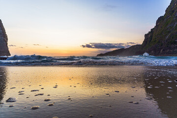 Aussicht auf den Sonnenuntergang bei rauem Wellengang am Kelingking Strand auf Bali in Indonesien.