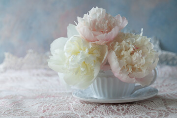 Light peonies in a cup on the table, beautiful still life, postcard