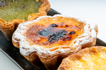 Freshly baked Egg tart in black plate on white background, Egg tart in black plate on white.