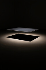 Floating dark platform casting a sharp shadow on illuminated floor