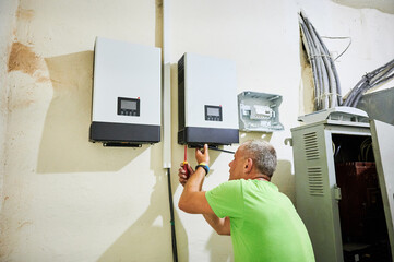 Man electrician installing solar panel system. Inspector making electrical wiring inverter and...
