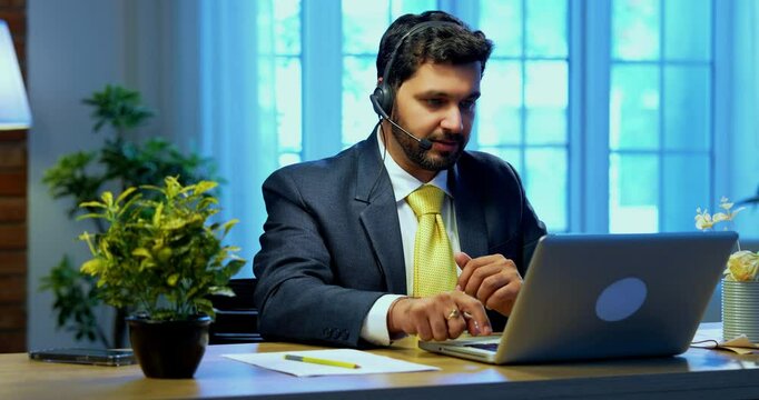 Indian businessman in call centre, Indian Asian corporate executive wearing headset and busy in communication, symbol of customer service, tech support, remote assistance, global connectivity