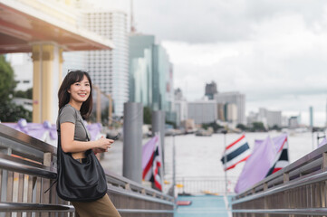 Happy young southeast asian woman travel blogger searching on smartphone map. World explorer...