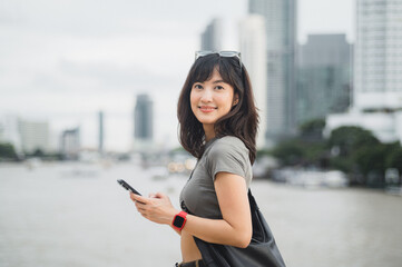 Happy young southeast asian woman teenager blogger using smartphone searching tourism guide. World...