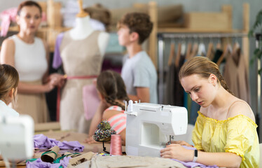 Teen girl child works with sewing machine and makes product during lesson at sewing school....