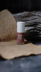 Glass bottle containing light brown liquid with white cap is placed on piece of weathered wood provides textured and natural element creating balanced aesthetic to the composition. 