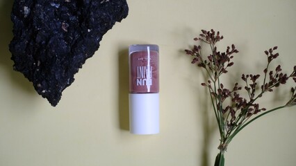 Glass bottle containing light brown liquid with white cap is placed on piece of weathered wood provides textured and natural element creating balanced aesthetic to the composition. 