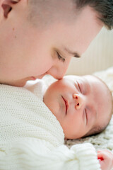 Closeup of a small newborn baby in the arms of his father. Dad hugs his little son.