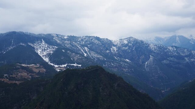 Majestic Haba Snow Mountain towers above forested terrain in Shangri-La&mdash;snowy peaks beneath a moody sky create a stunning portrait of Yunnan&rsquo;s alpine wilderness.
