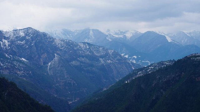 Majestic Haba Snow Mountain towers above forested terrain in Shangri-La&mdash;snowy peaks beneath a moody sky create a stunning portrait of Yunnan&rsquo;s alpine wilderness.