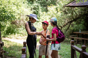 Family hiking in forest using trekking poles and checking smartwatch