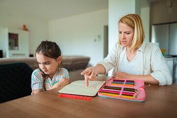 Mother guides daughter during art time at home