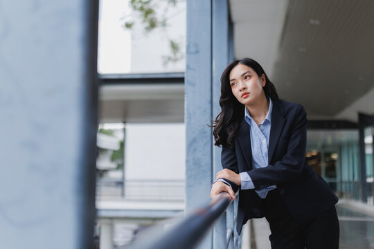 Pensive businesswoman leaning on railing and looking away