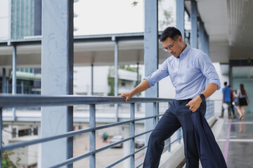 Tired businessman leaning on railing in modern city setting