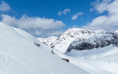 Alpine skiers in mountain. Group of downhill skiers on a slope on a bright sunny day. Norwegians...