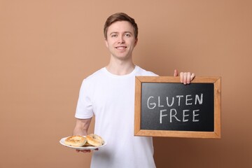 Man holding small chalkboard with text Gluten Free and pretzels on beige background
