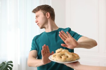 Gluten free diet. Man refusing from pastries indoors, selective focus