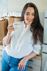 Young woman drinking hot coffee at home in the kitchen.