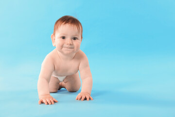 Cute little baby crawling on light blue background. Space for text