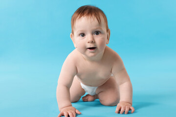 Cute little baby crawling on light blue background
