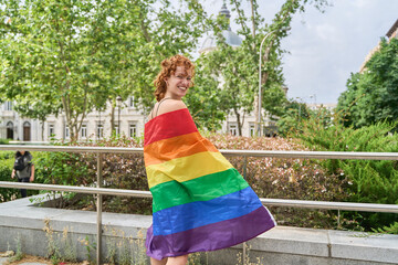 Young woman showing rainbow flag at gay pride, celebrating lgbtq plus community
