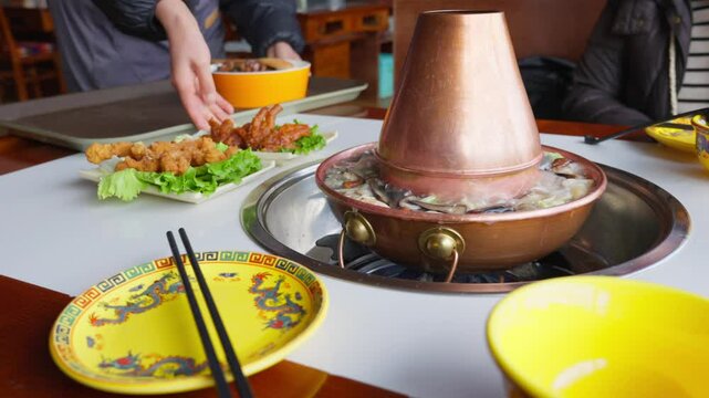 A copper pot of bubbling Tibetan mushroom hot pot anchors a vibrant dining scene&mdash;featuring floral dishes, shared platters, and warm cultural hospitality.