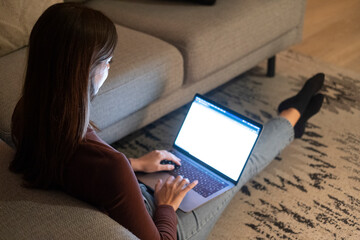 Young woman working late at home with warm lamp light – student or freelancer using laptop for...