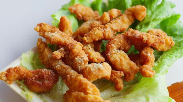 Golden fried pork strips rest atop fresh lettuce&mdash;showcasing crunchy texture, savory warmth, and vibrant plating of a beloved Chinese delicacy.