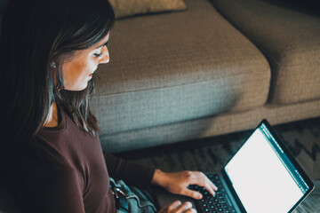 Young woman working late at home with warm lamp light – student or freelancer using laptop for...