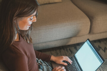 Young woman working late at home with warm lamp light – student or freelancer using laptop for...