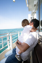 A man and a boy on a white boat in the sea are sitting by the side, father and son are enjoying a...