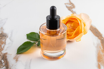Glass Dropper Bottle with Natural Face and Body Skin Care on Marble Abstract Tea Rose Background. A blank bottle mockup. Natural organic care.
