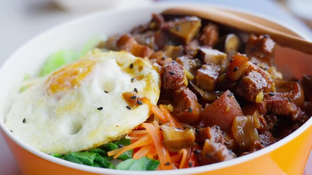 A bowl of braised pork rice topped with a golden fried egg, carrots, and greens&mdash;capturing savory depth, comforting texture, and vibrant plating in Chinese homestyle cuisine.
