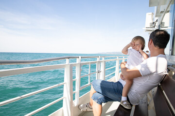 A man and a boy on a white boat in the sea are sitting by the side, father and son are enjoying a sea trip