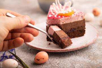 Chocolate cake with hand on brown concrete, cup of coffee, side view, close up, selective focus