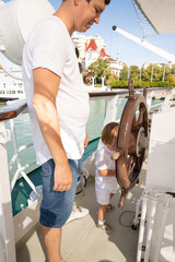 A man and a boy on a white boat in the sea are sitting by the side, father and son are enjoying a sea trip