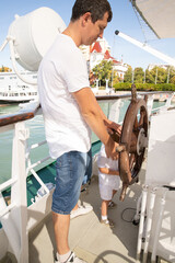A man and a boy on a white boat in the sea are sitting by the side, father and son are enjoying a sea trip