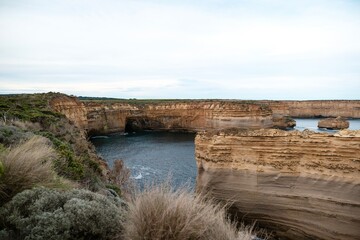 Dramatic coastal scene of Loch Ard Gorge's Shipwreck Point. Rugged cliffs frame a small sandy beach...