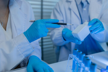 two scientists consult each other while conducting an experiment on a liquid substance in a...