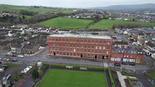 Aerial view of a historic red-brick building with green fields in background in Derry