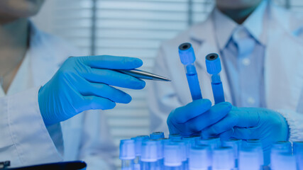 two scientists consult each other while conducting an experiment on a liquid substance in a...